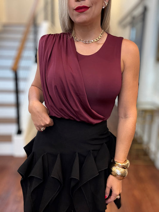 Burgundy sleeveless bodysuit with draped front and black ruffled skirt, close-up