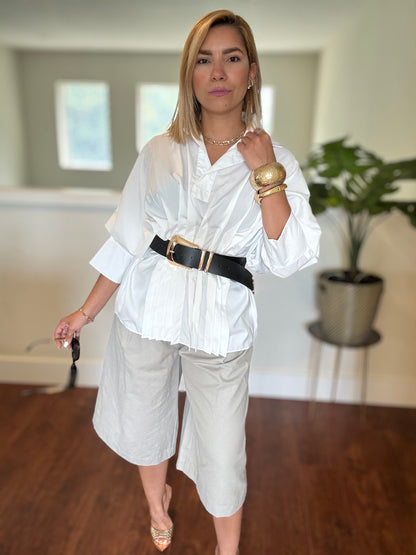 White button-up peplum top with short sleeves, V-neck placket, and layered hem