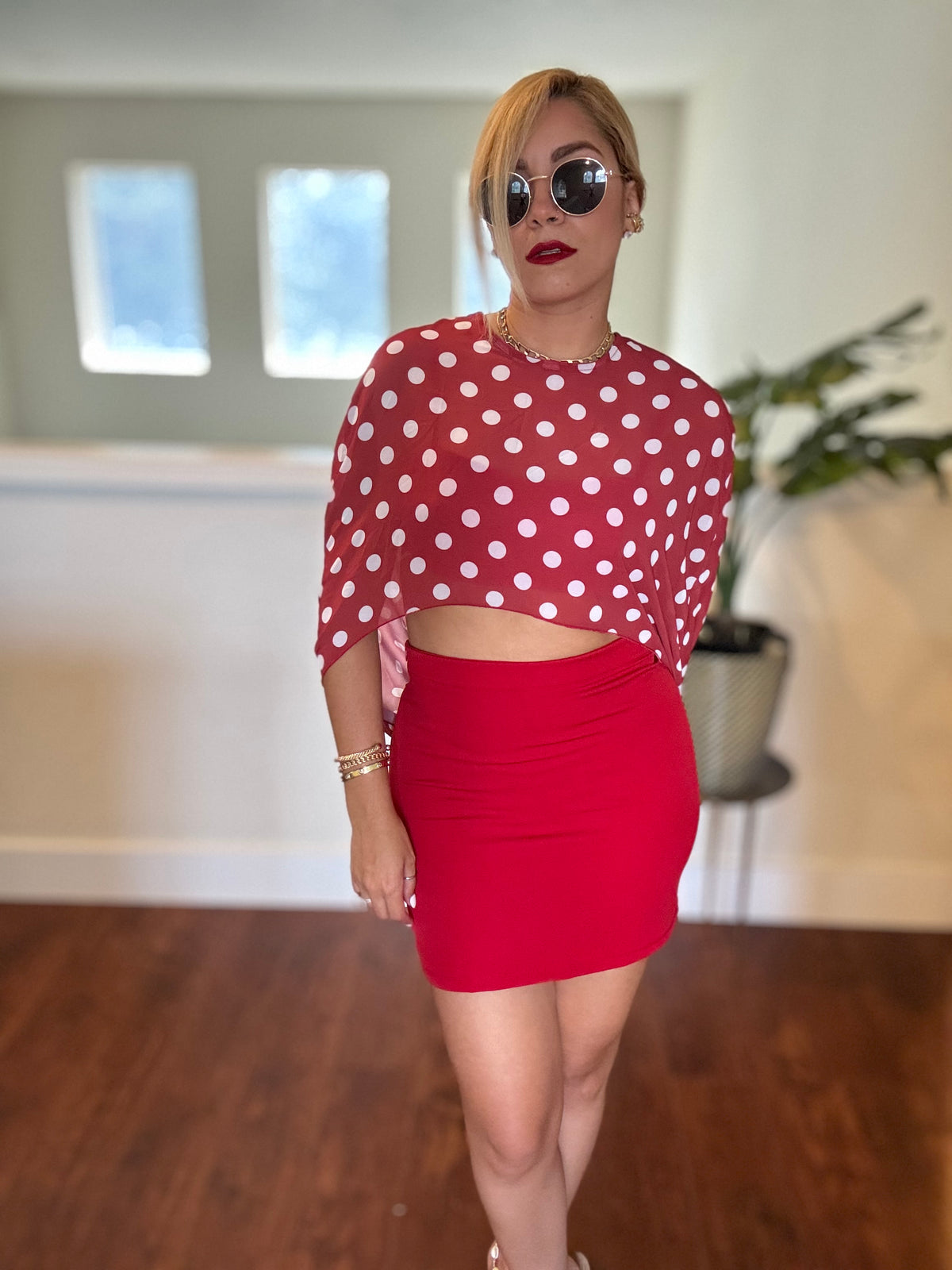Red bandeau crop top and mini skirt with white polka-dot sheer wrap draped down.