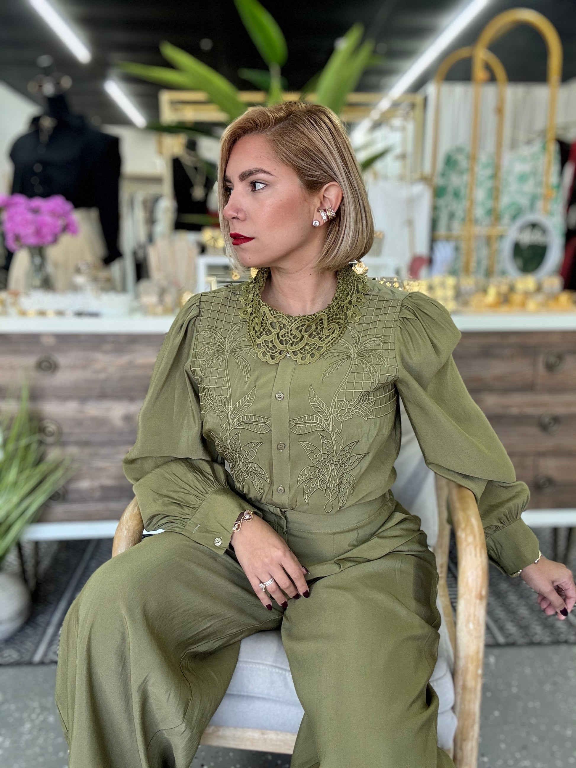 Olive green blouse and wide-leg pants set, seated side angle with button placket