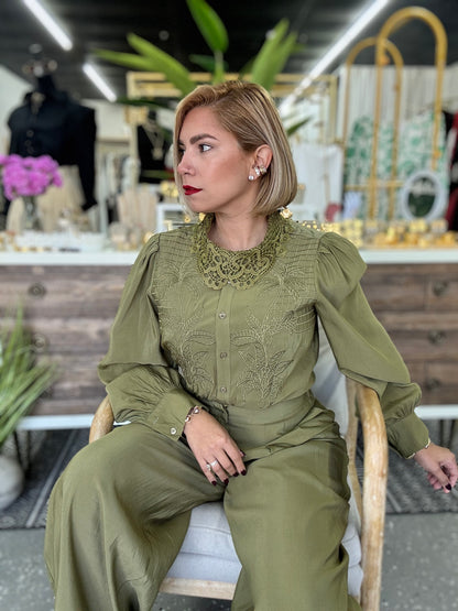 Olive green blouse and wide-leg pants set, seated side angle with button placket