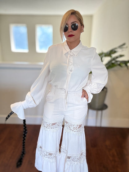 White lace-trim jumpsuit with button placket, drawstring neck tie, and flared hem