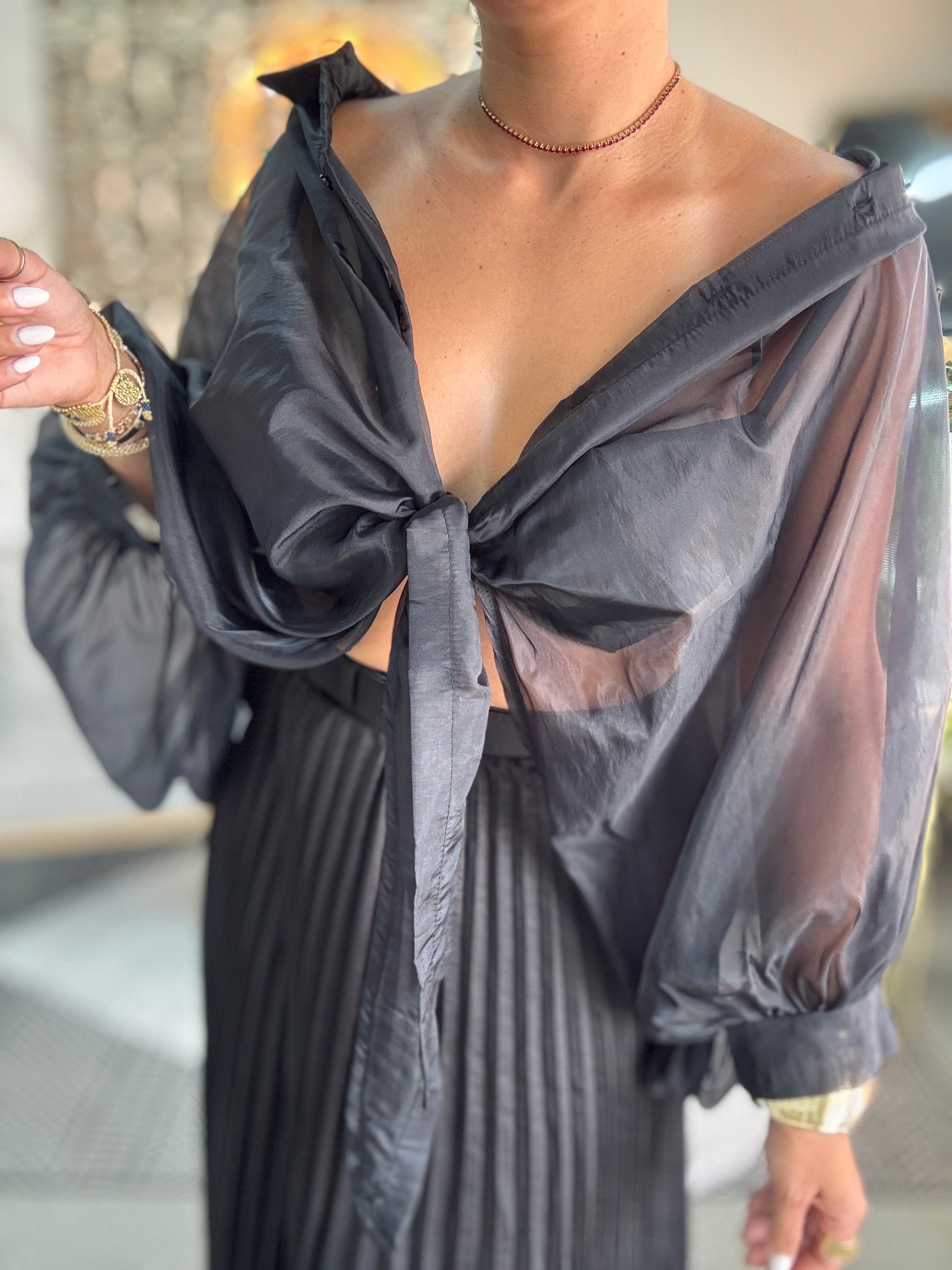 Luxury top close-up: draped off-shoulder neckline, bow tie, puff sleeve cuff