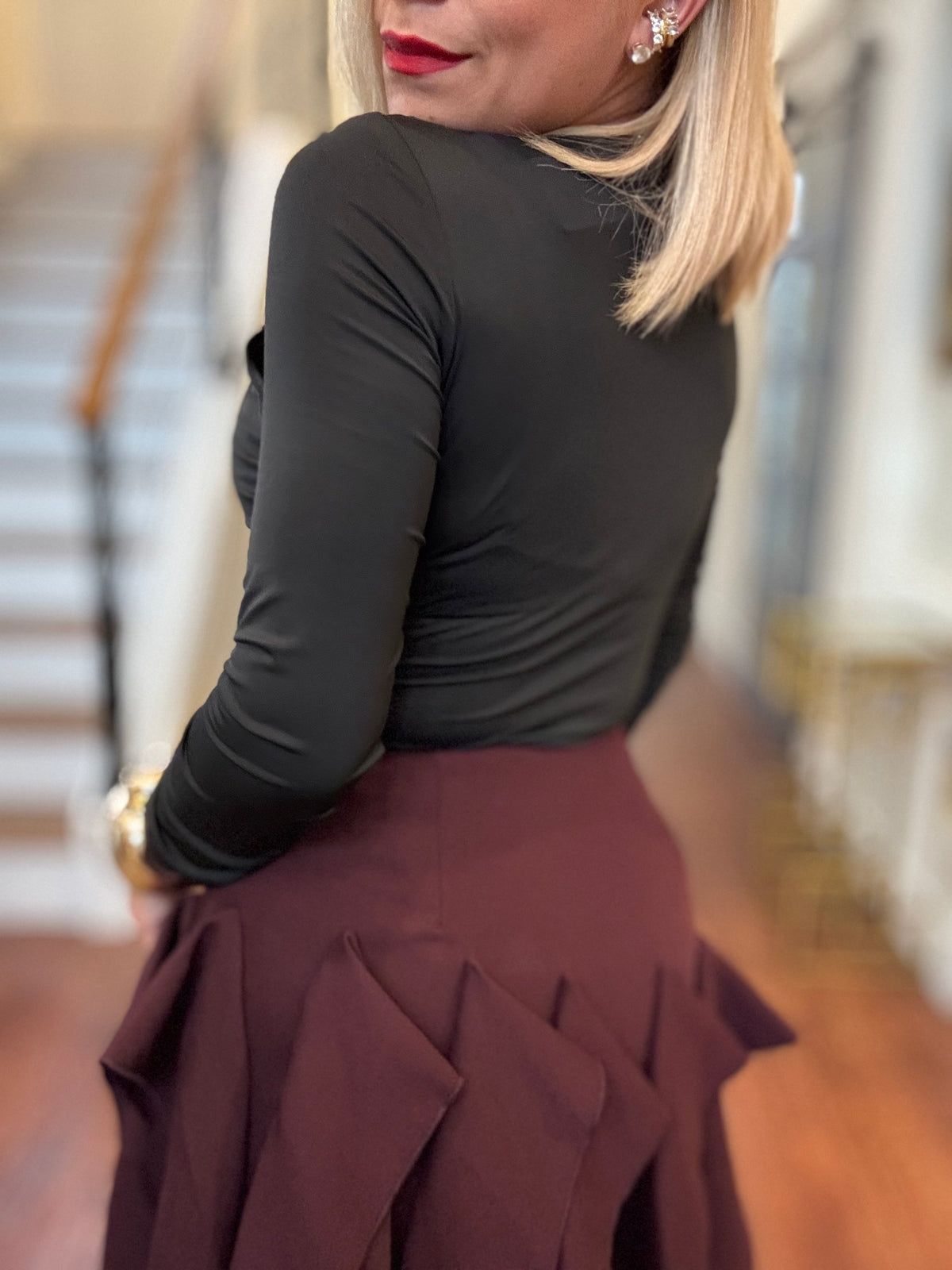 Side view of black long-sleeve fitted bodysuit with draped crossover