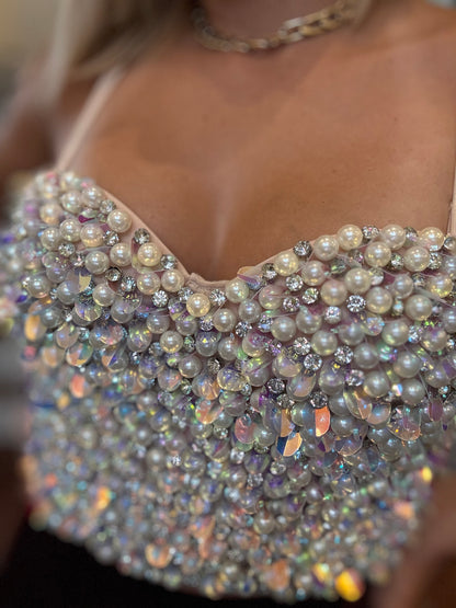 Close-up of nude bustier cups with iridescent rhinestones, pearls, and bead fringe