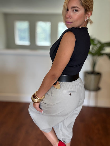 Black sleeveless top and white belted shorts, side view with gold bracelets