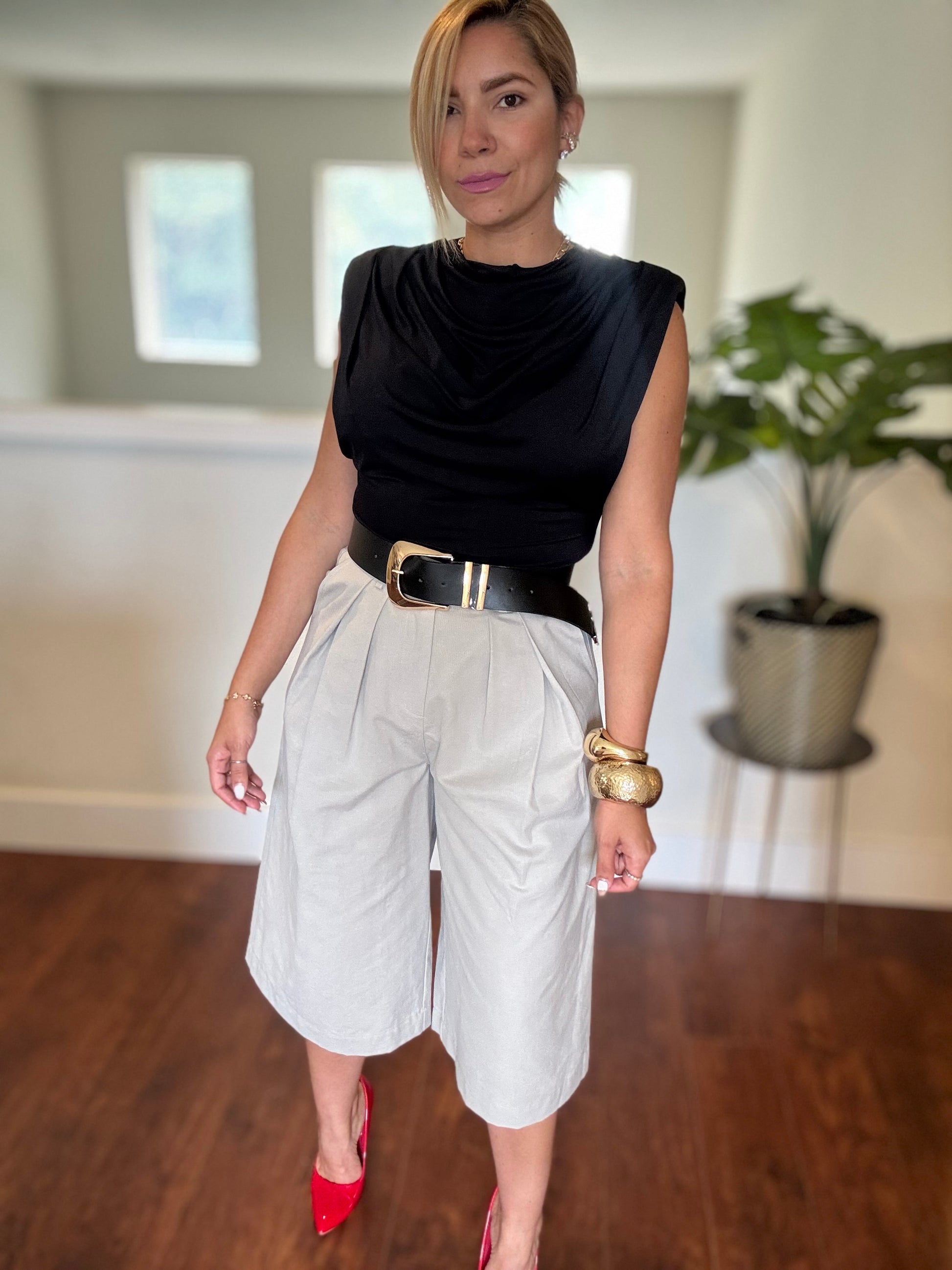 Black sleeveless top with draped neckline and white belted shorts, full body