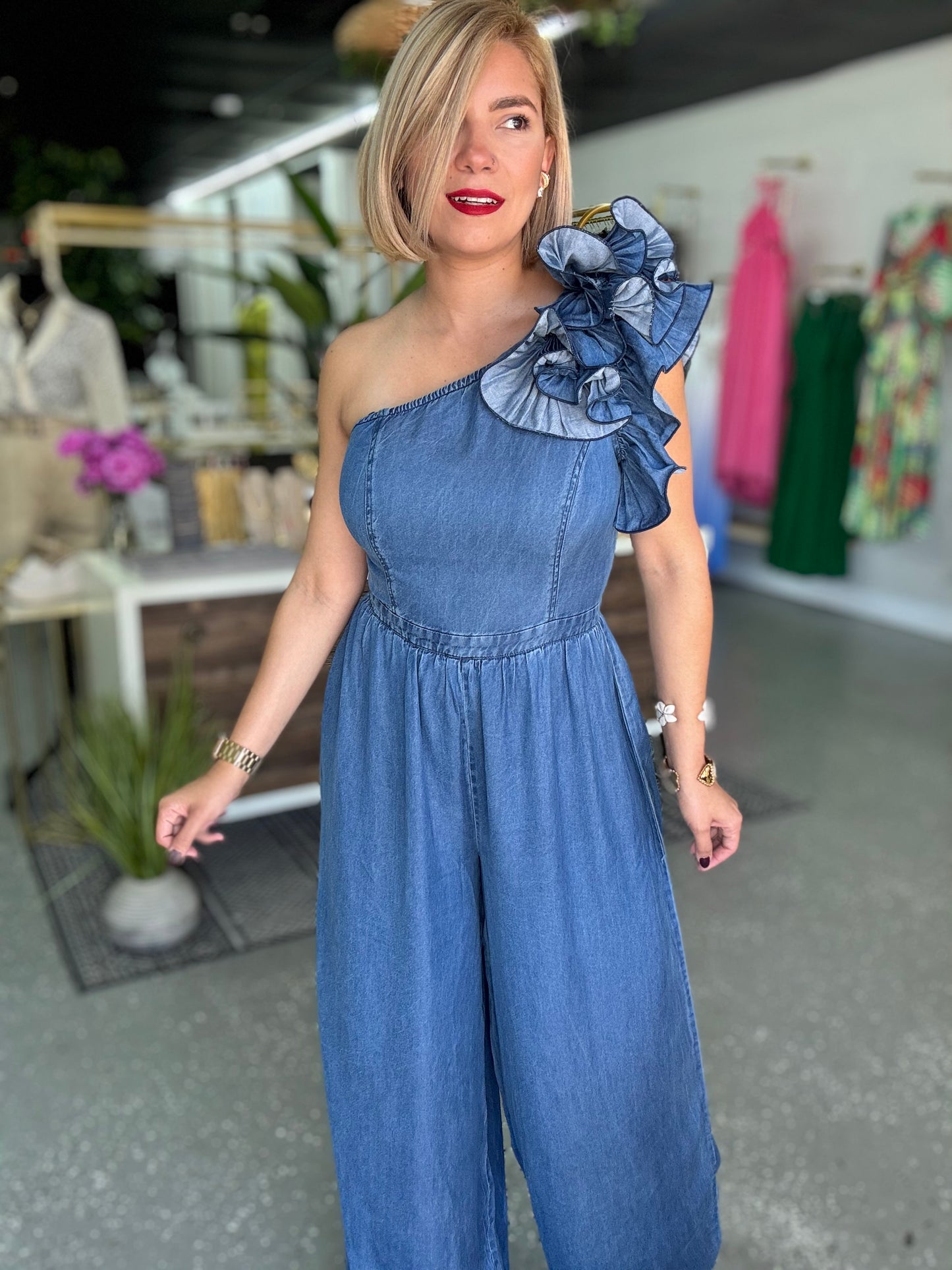 Blue denim one-shoulder jumpsuit with ruffled shoulder detail and wide legs