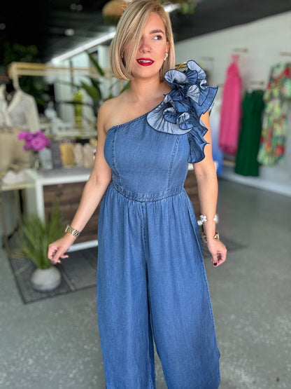 Blue denim one-shoulder jumpsuit with ruffled shoulder detail and wide legs