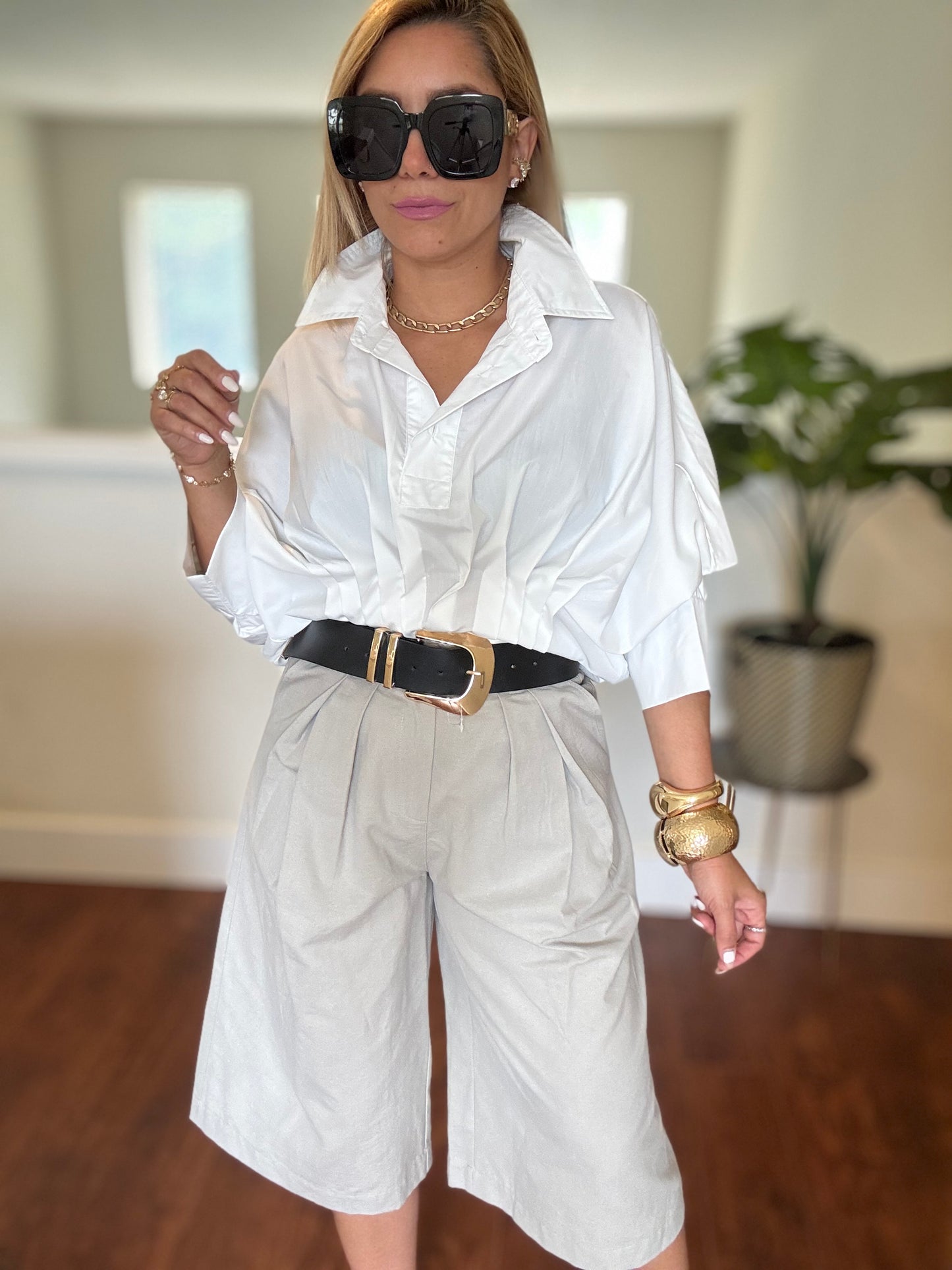 White button-up blouse, black belt, and white belted shorts with sunglasses