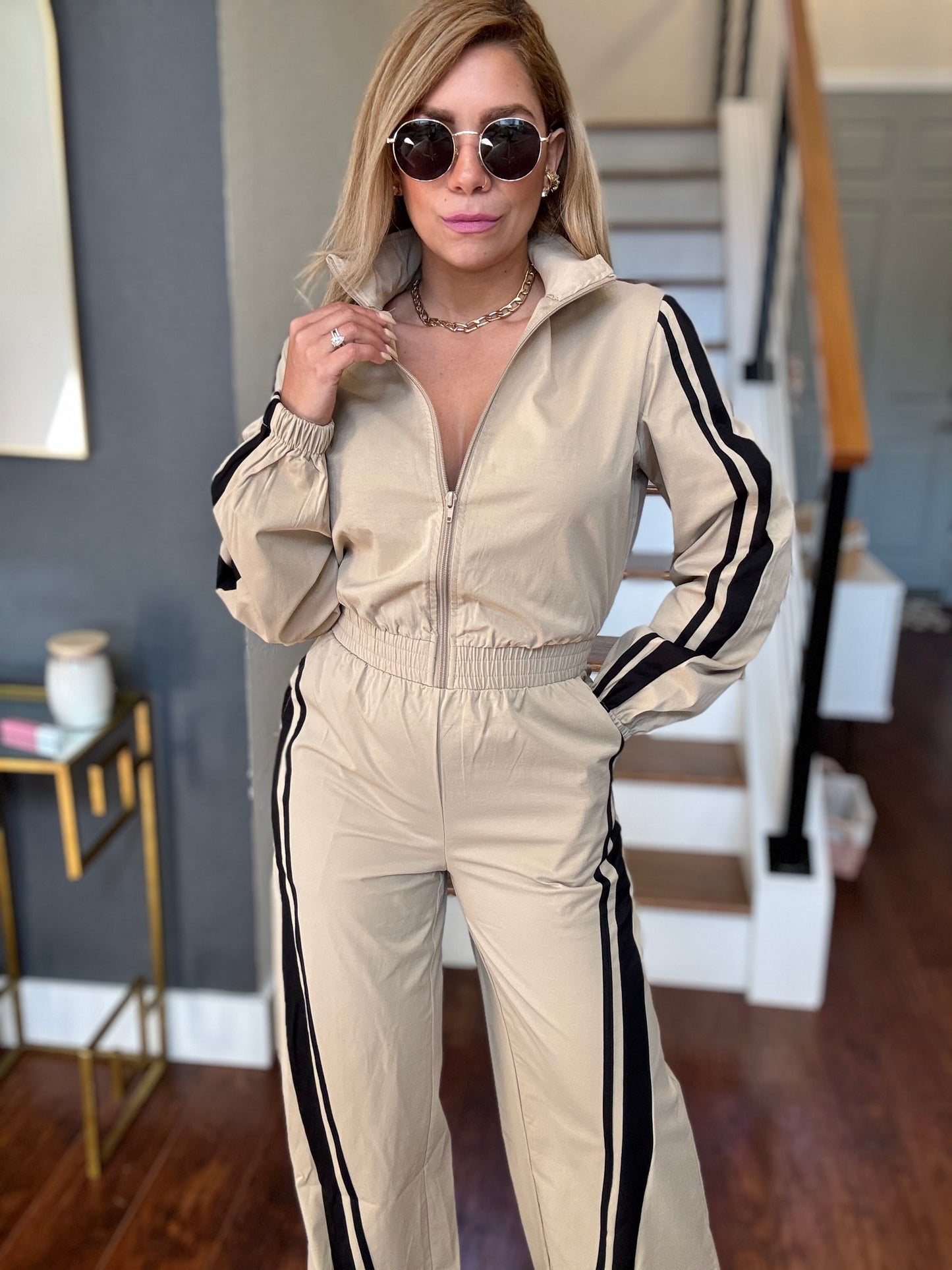 Bianca Fly jumpsuit in beige with full zip front, hood, and black side stripe accents