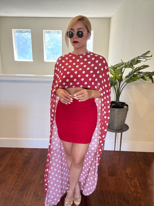Red bandeau crop top and mini skirt with long polka-dot sheer wrap covering arms.