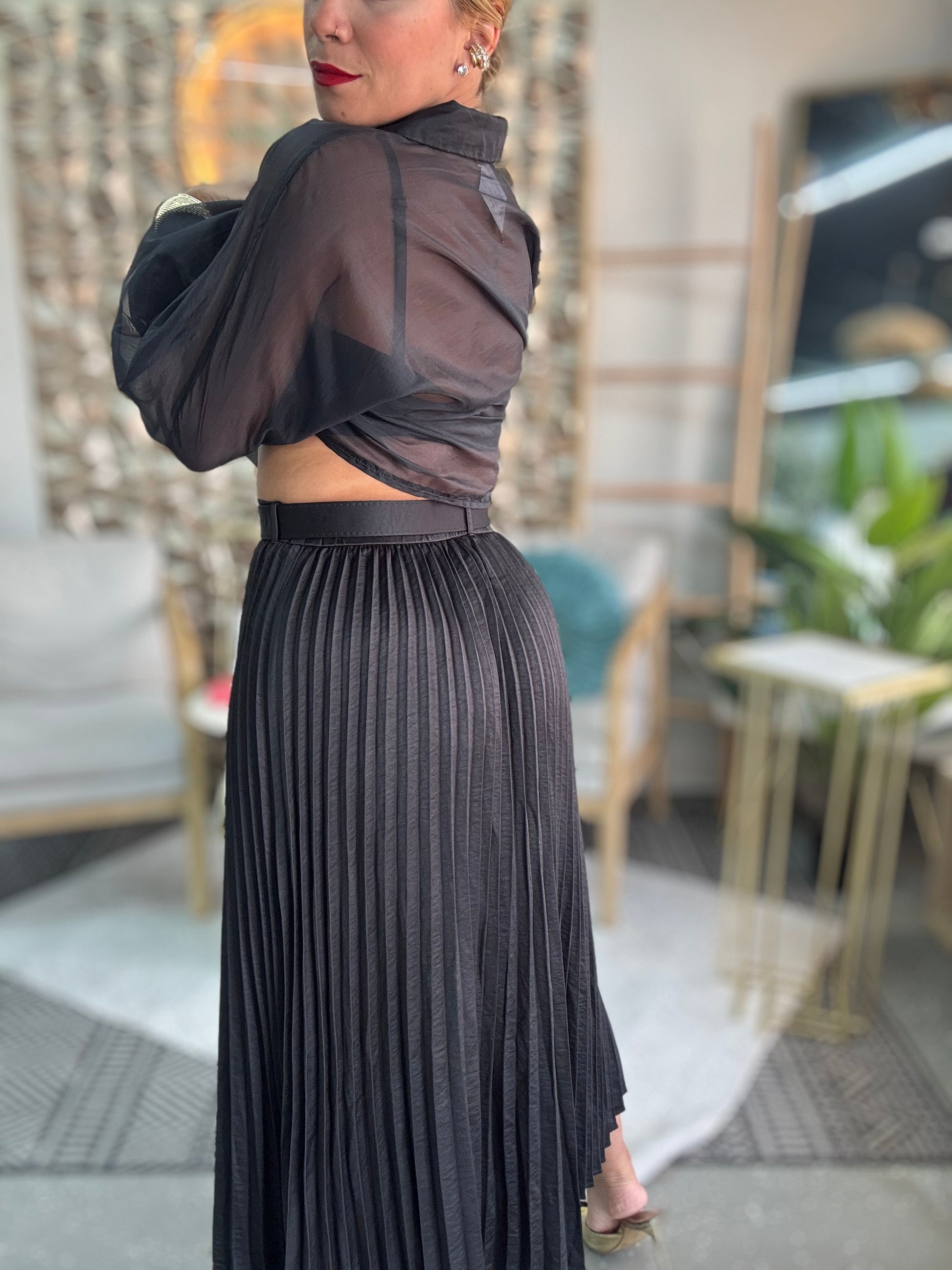 Black pleated midi skirt showing vertical rib texture and gathered elastic waistband