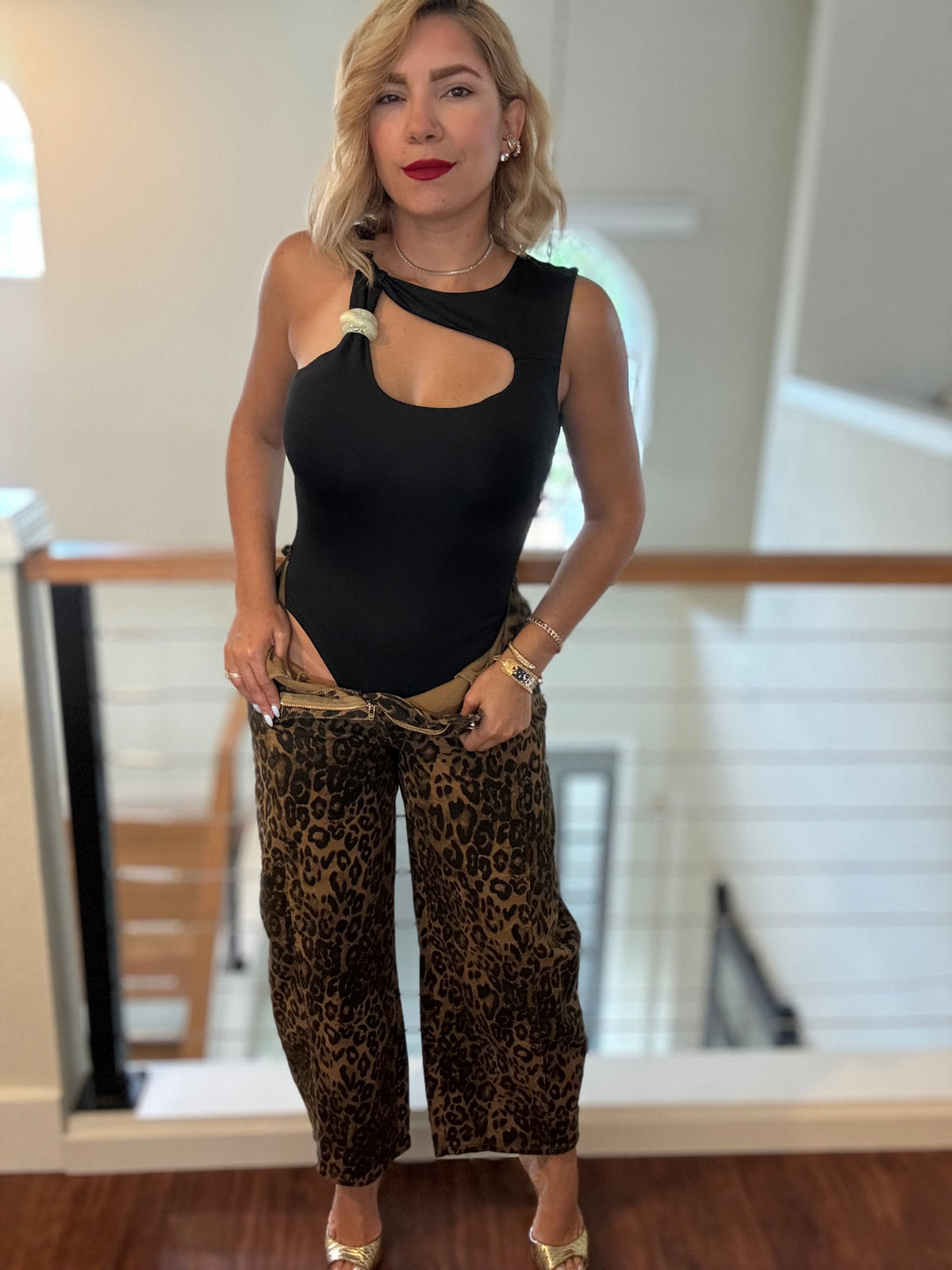 Black sleeveless bodysuit with chest keyhole cutout and pom-pom shoulder ties