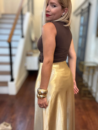Gold satin midi skirt shown from the side with smooth, reflective fabric