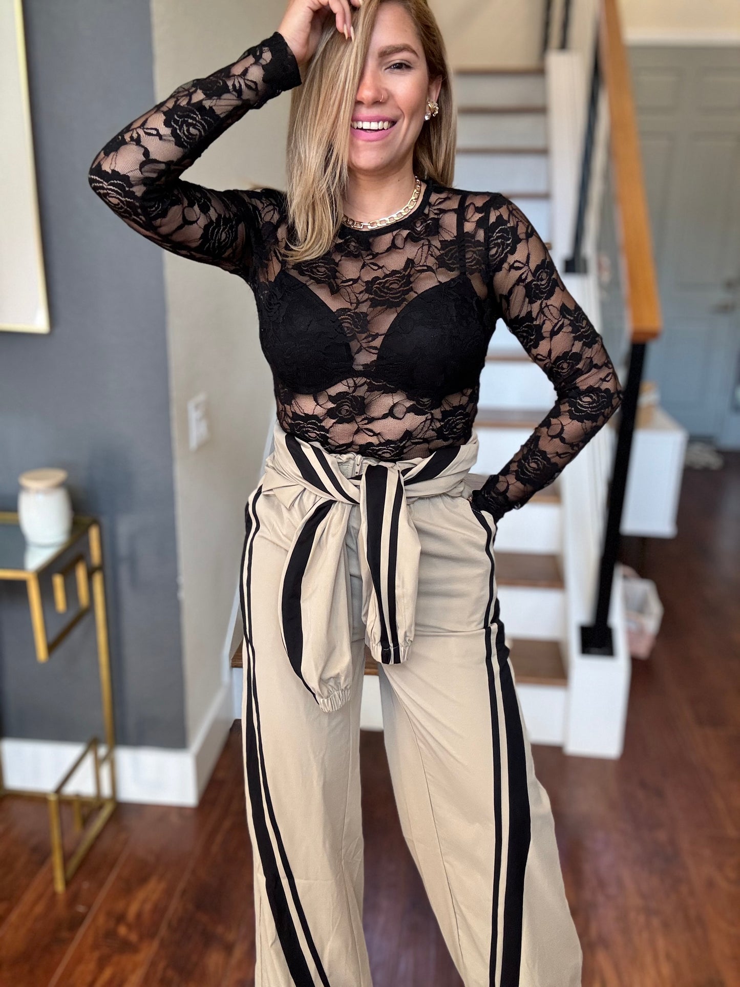 Bianca Fly jumpsuit with black lace bodice, beige pants, and tied fabric detail at waist