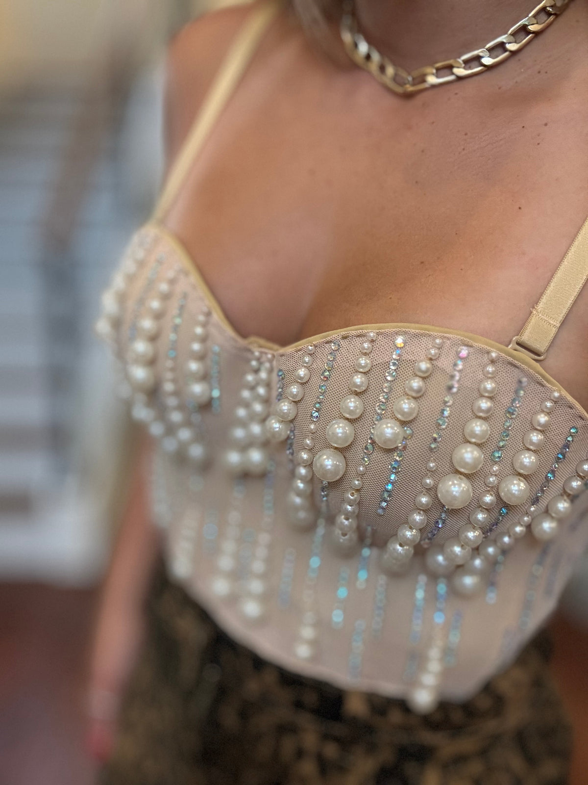 Close-up of pearl-beaded heart bustier with dangling bead fringe on nude satin