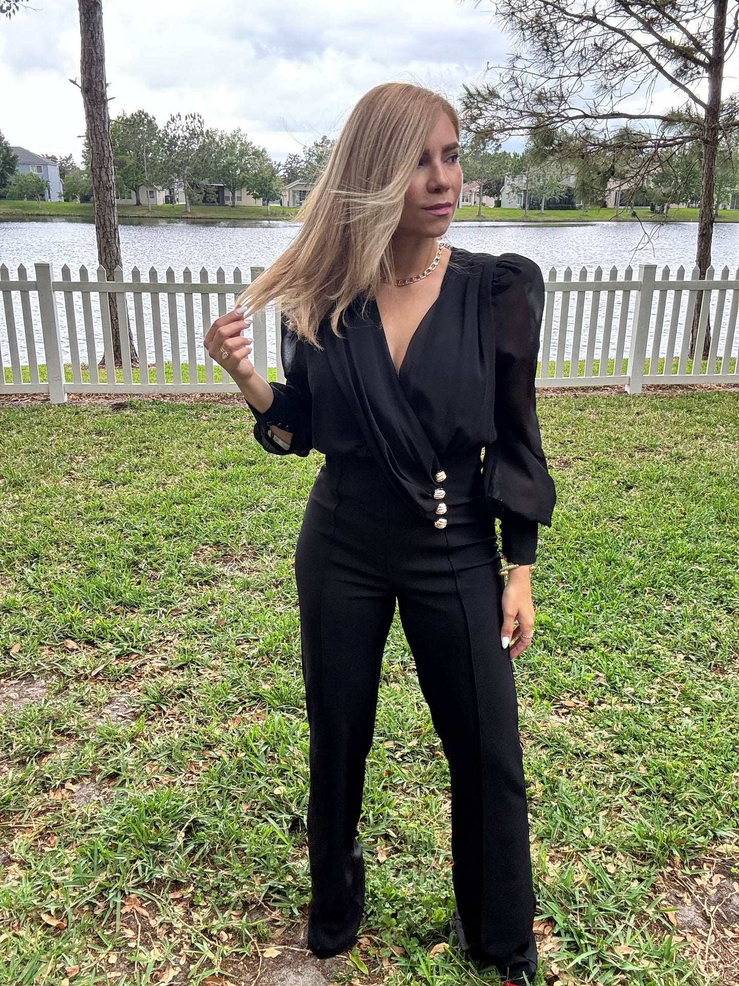 Black V-neck jumpsuit with long puff sleeves, gold button waist detail