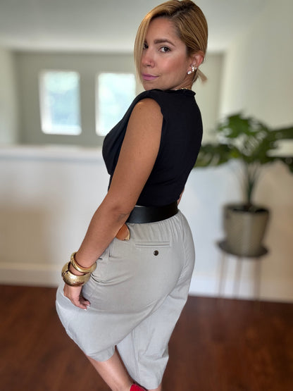 Black sleeveless top and white belted shorts, side view