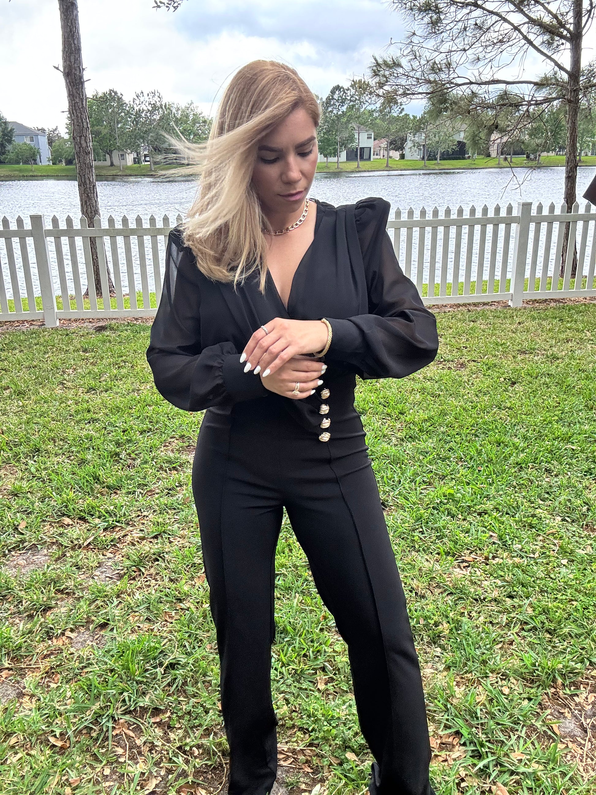 Black V-neck jumpsuit with long puff sleeves and gold button waist detail