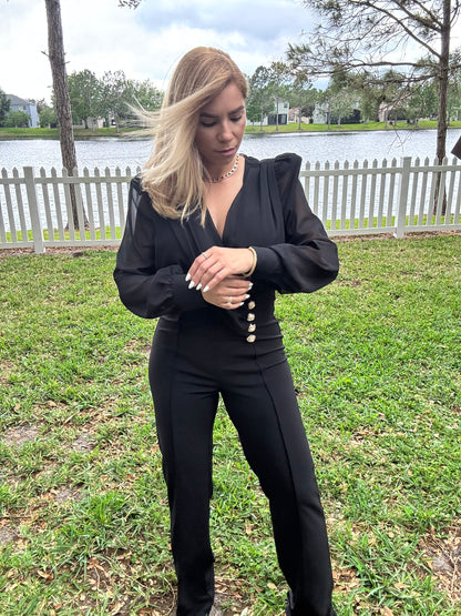 Black V-neck jumpsuit with long puff sleeves and gold button waist detail