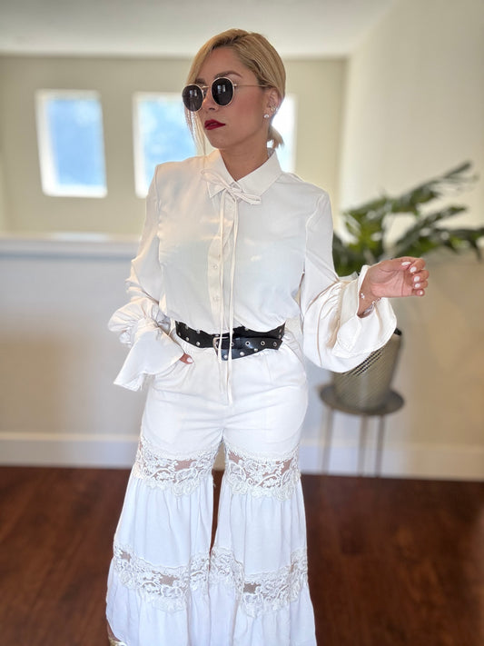 White lace-panel jumpsuit with long cuffed sleeves and black studded waist belt
