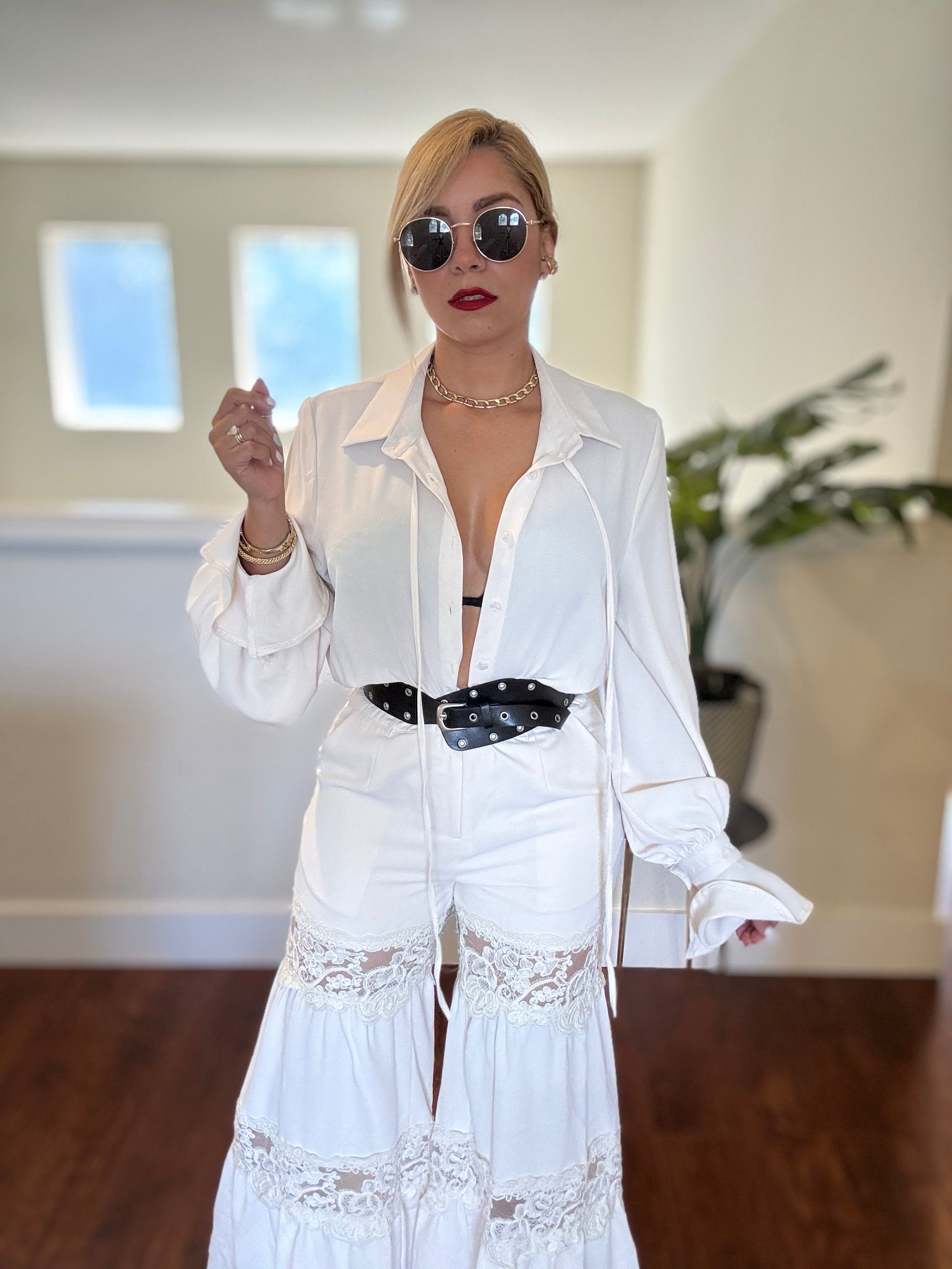 White button-front jumpsuit with long sleeves, lace paneling at cuffs and hem, belt