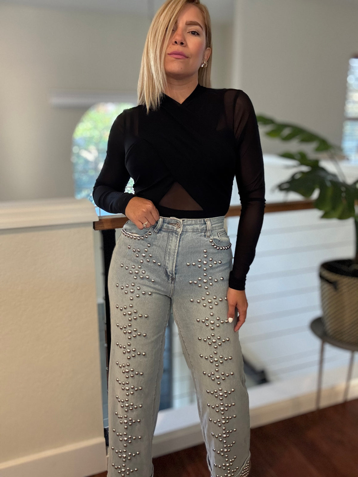 Light-wash denim jeans covered in silver-tone stud details on front
