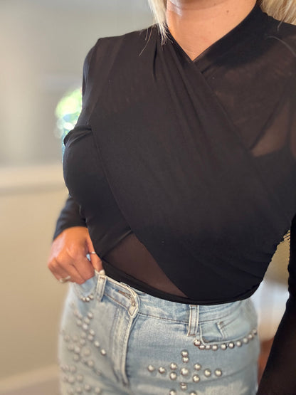 Black draped bodysuit close-up with V neckline and sheer long sleeves