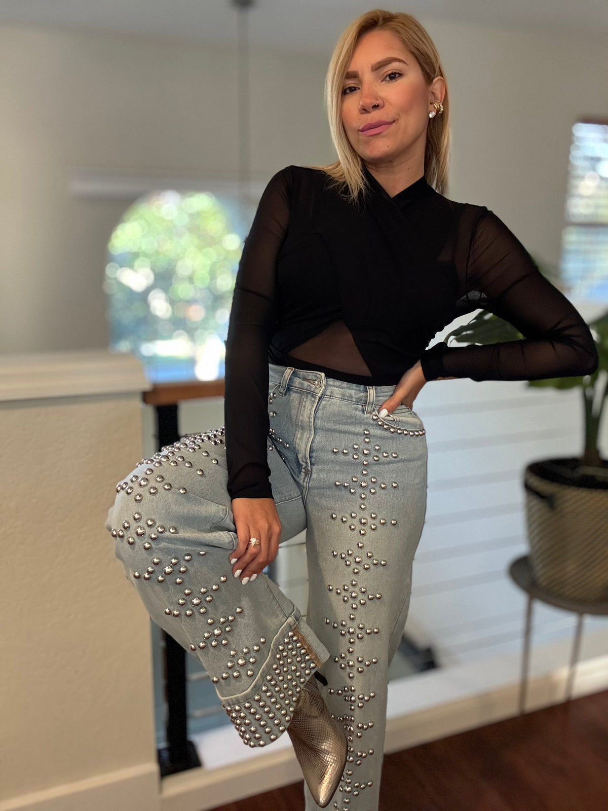 Light-wash studded jeans with dense silver-tone studs on thighs and pockets